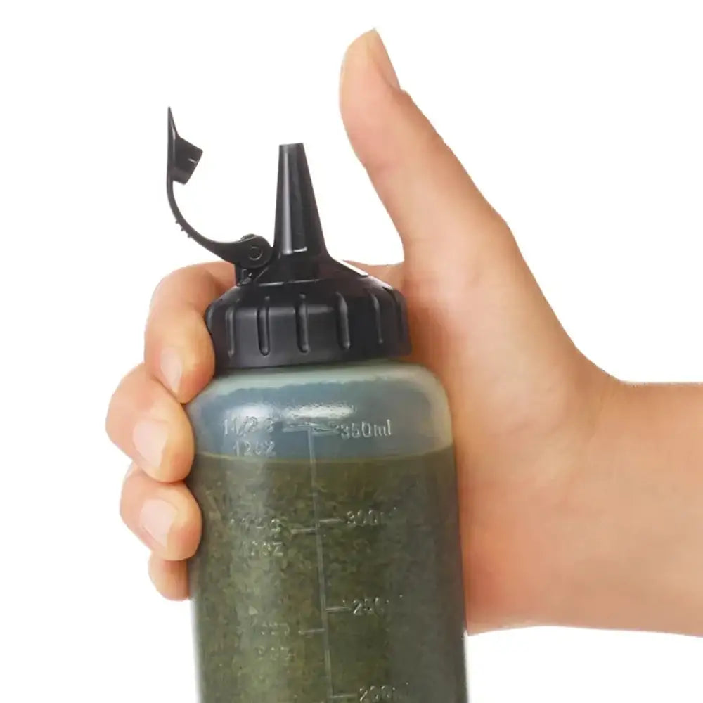 Hand holding a green bottle with a black cap on a white background