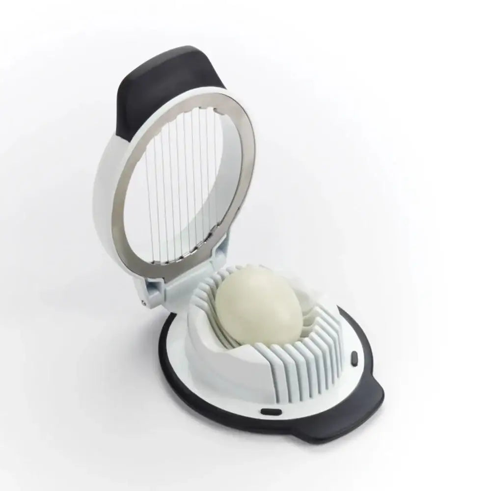 White and black egg slicer with an egg inside on a white background