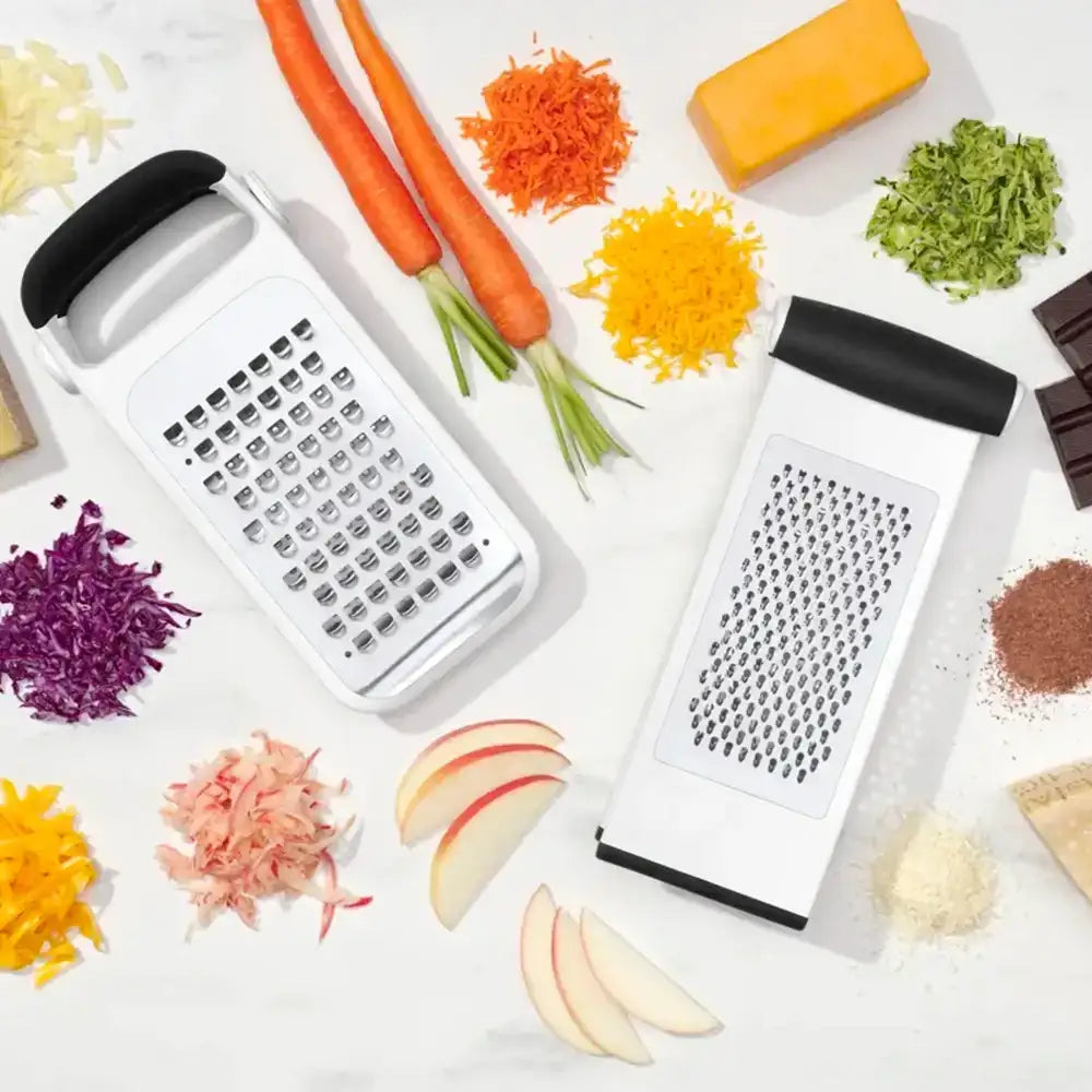 Two box graters with shredded vegetables and fruits on a white background