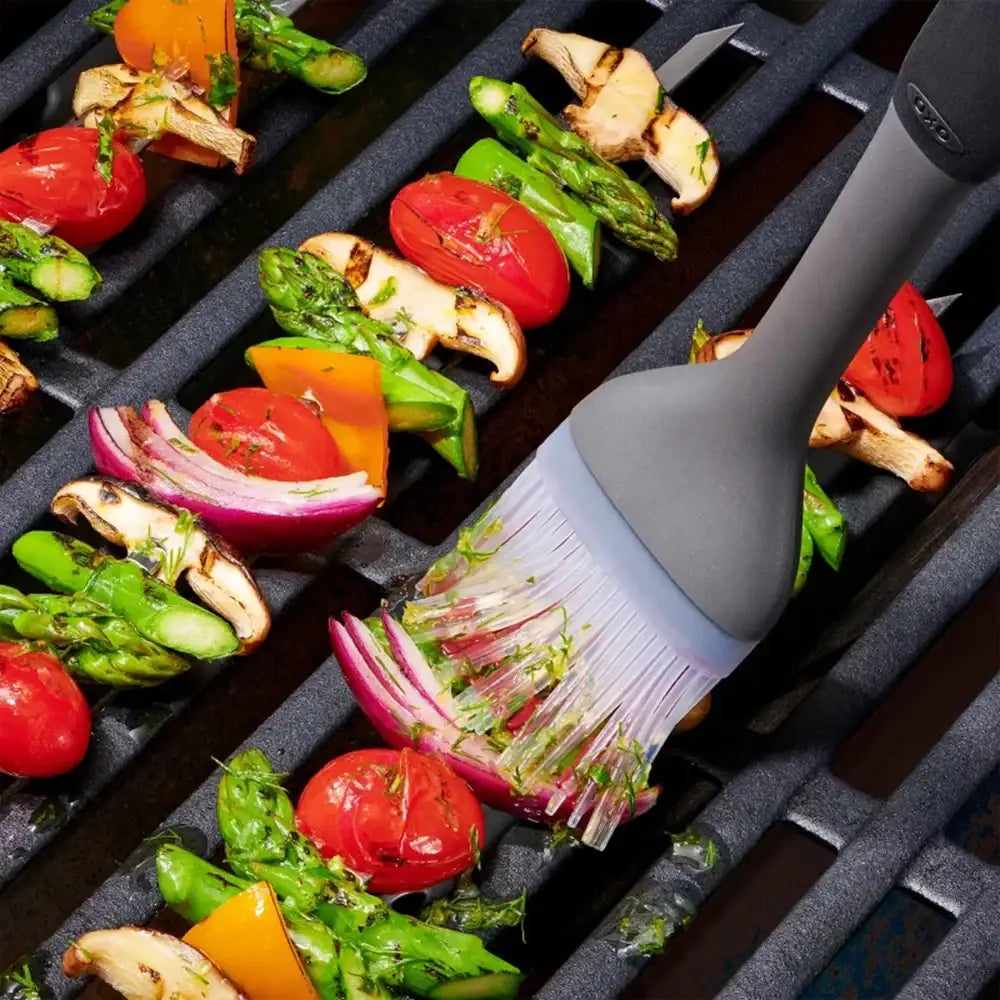 Grilled vegetables on a grill with a basting brush.