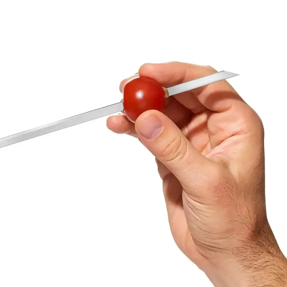 Hand holding a red cherry with a white string against a white background