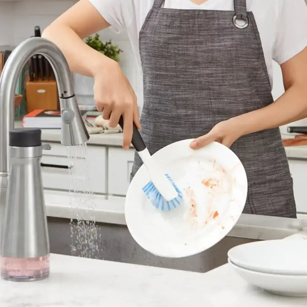 Person washing a plate with a scrubber in a kitchen setting