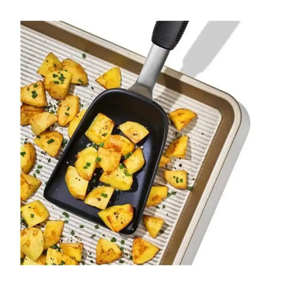 Roasted potatoes on a baking tray with a black spatula