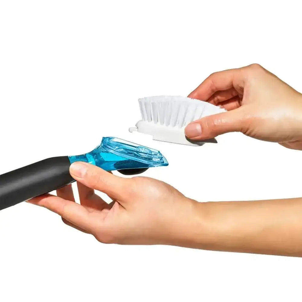 Person holding a cleaning brush with a blue base and white bristle head on a white background