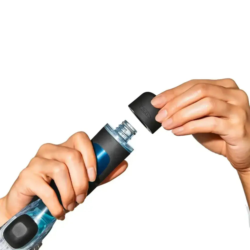 Person holding a soap dispensing brush with black cap on a white background