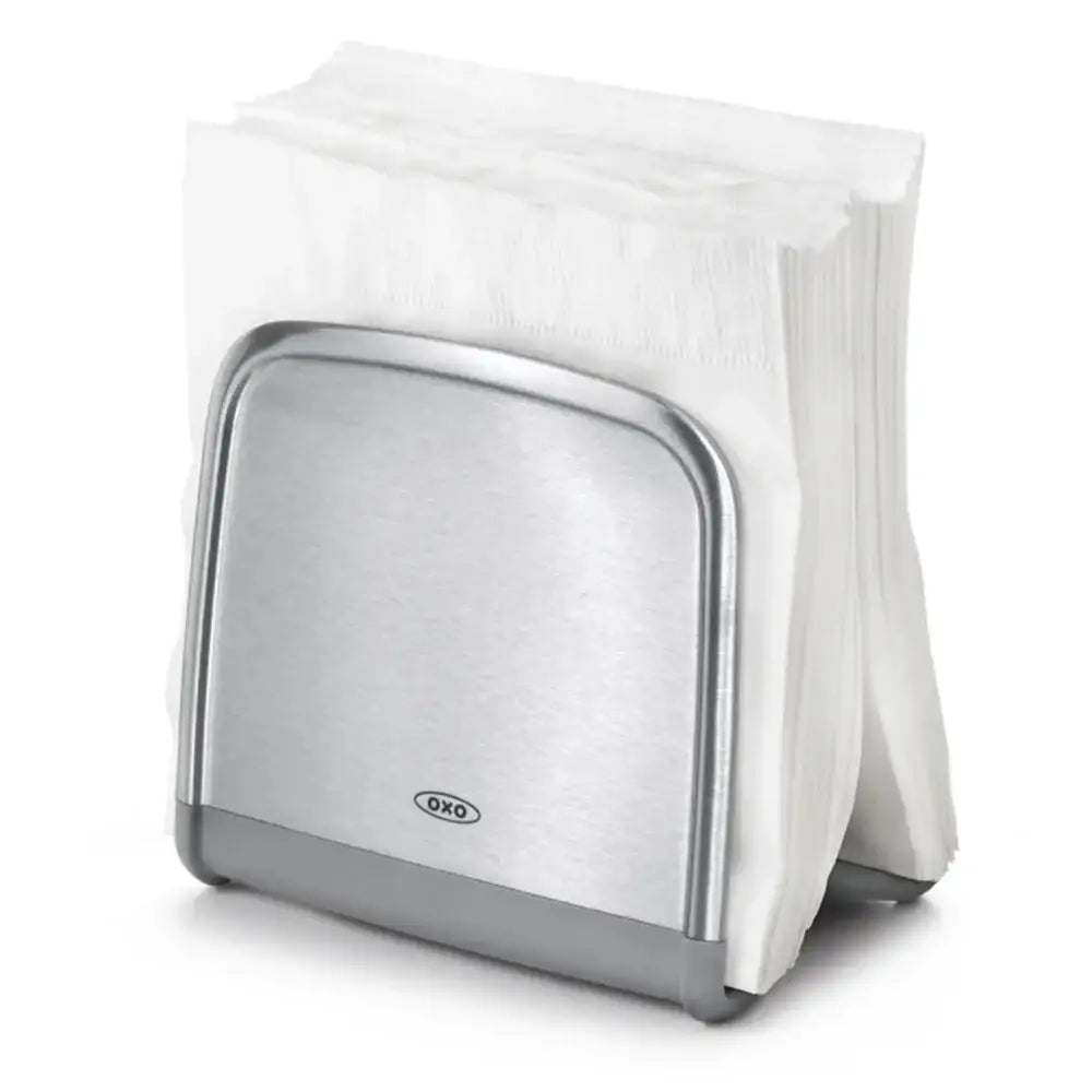 Metallic napkin holder with a stack of white napkins on a white background
