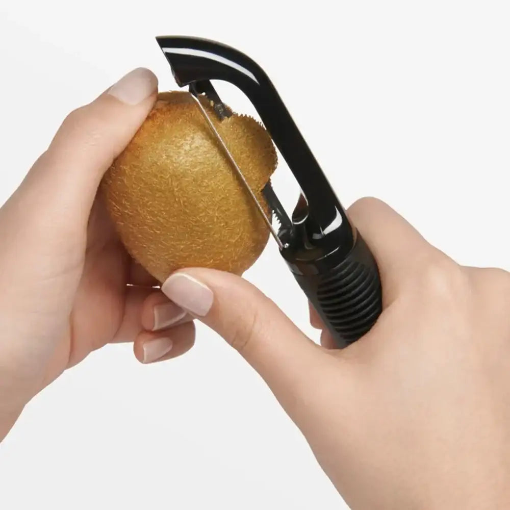 Person using a kiwi peeler to cut a kiwi fruit on a white background