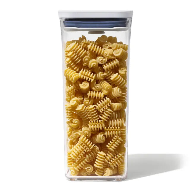 Clear container filled with spiral pasta on a white background