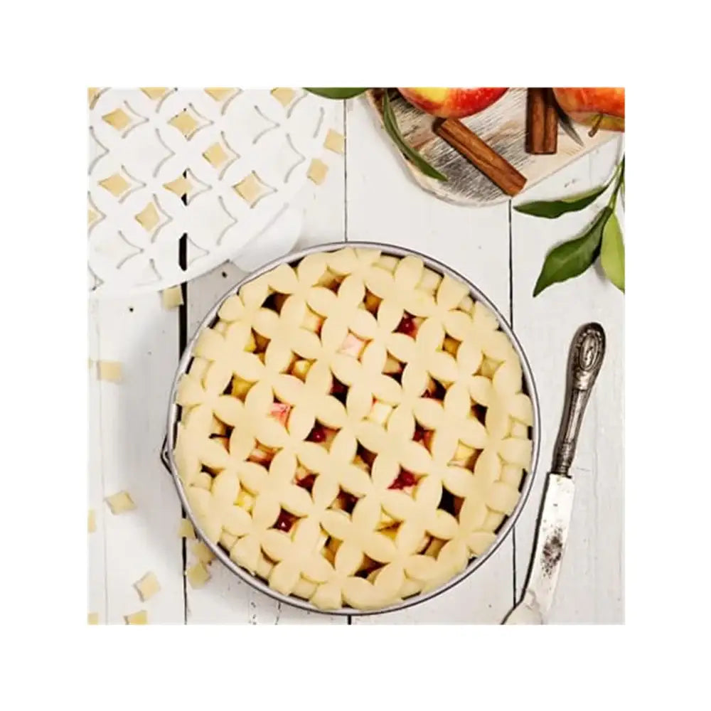 Unbaked pie with lattice crust on a wooden table with apples and cinnamon sticks.