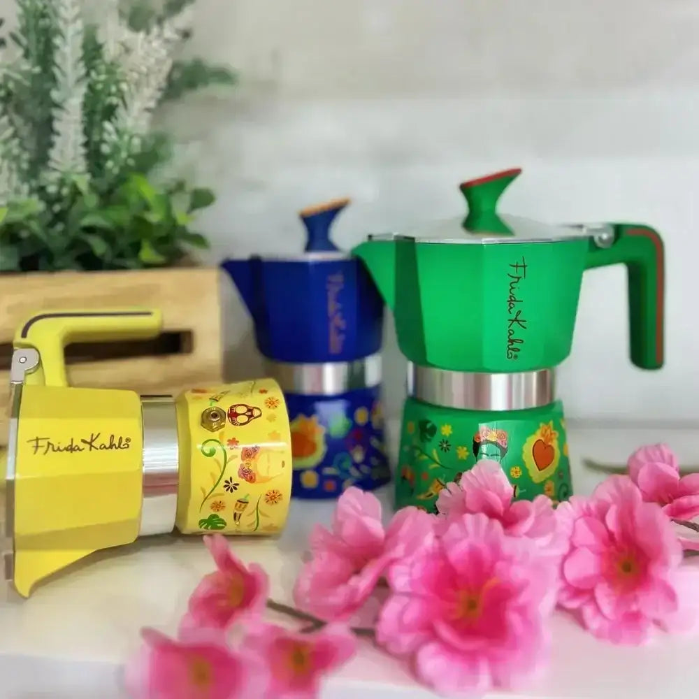 Colorful coffee makers with floral designs on a white surface with pink flowers.