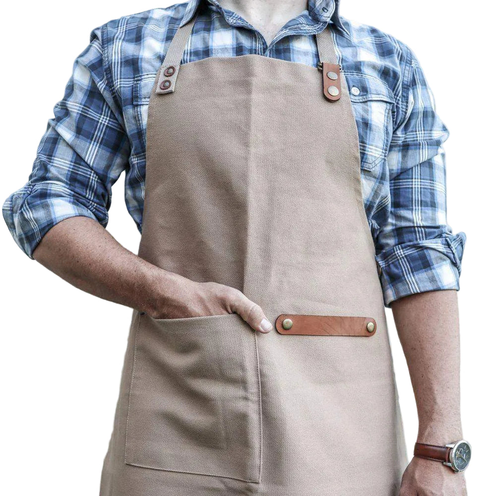 Person wearing a beige apron with brown leather straps against a plain background