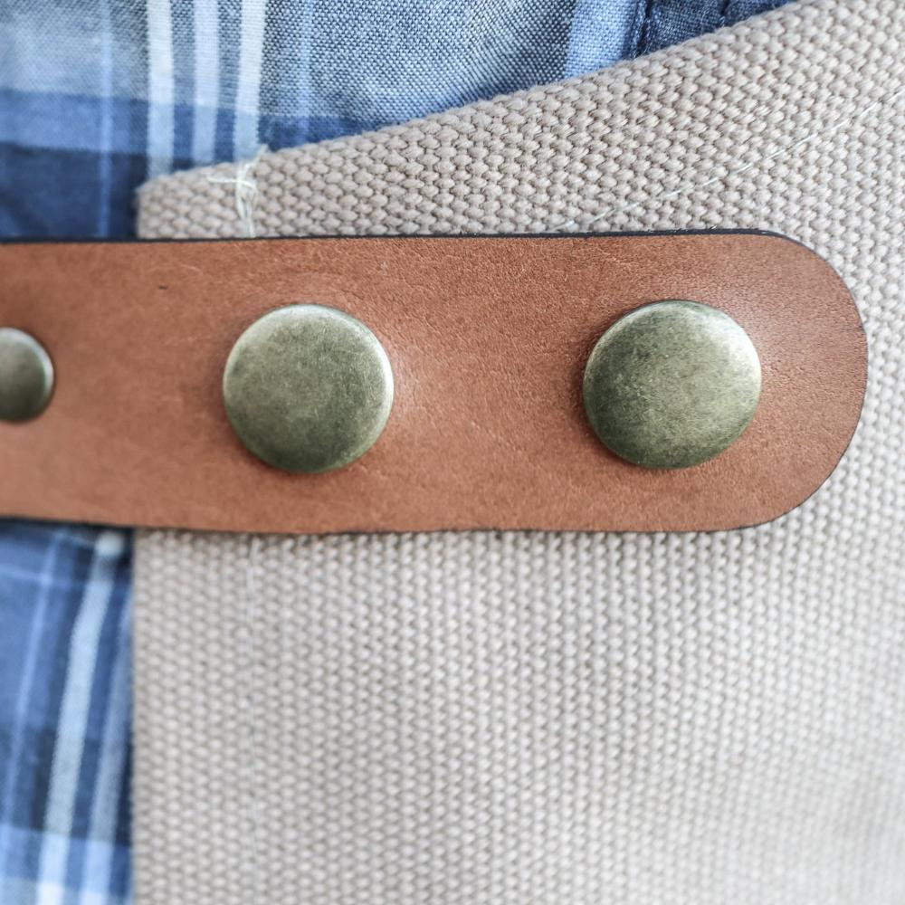 Close-up of a leather strap with metal buttons on a fabric background