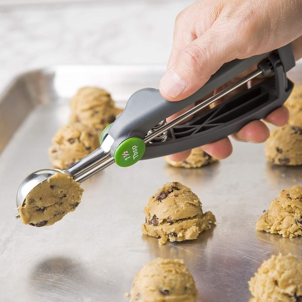 Cookie dough being scooped onto a baking sheet with a cookie scoop.