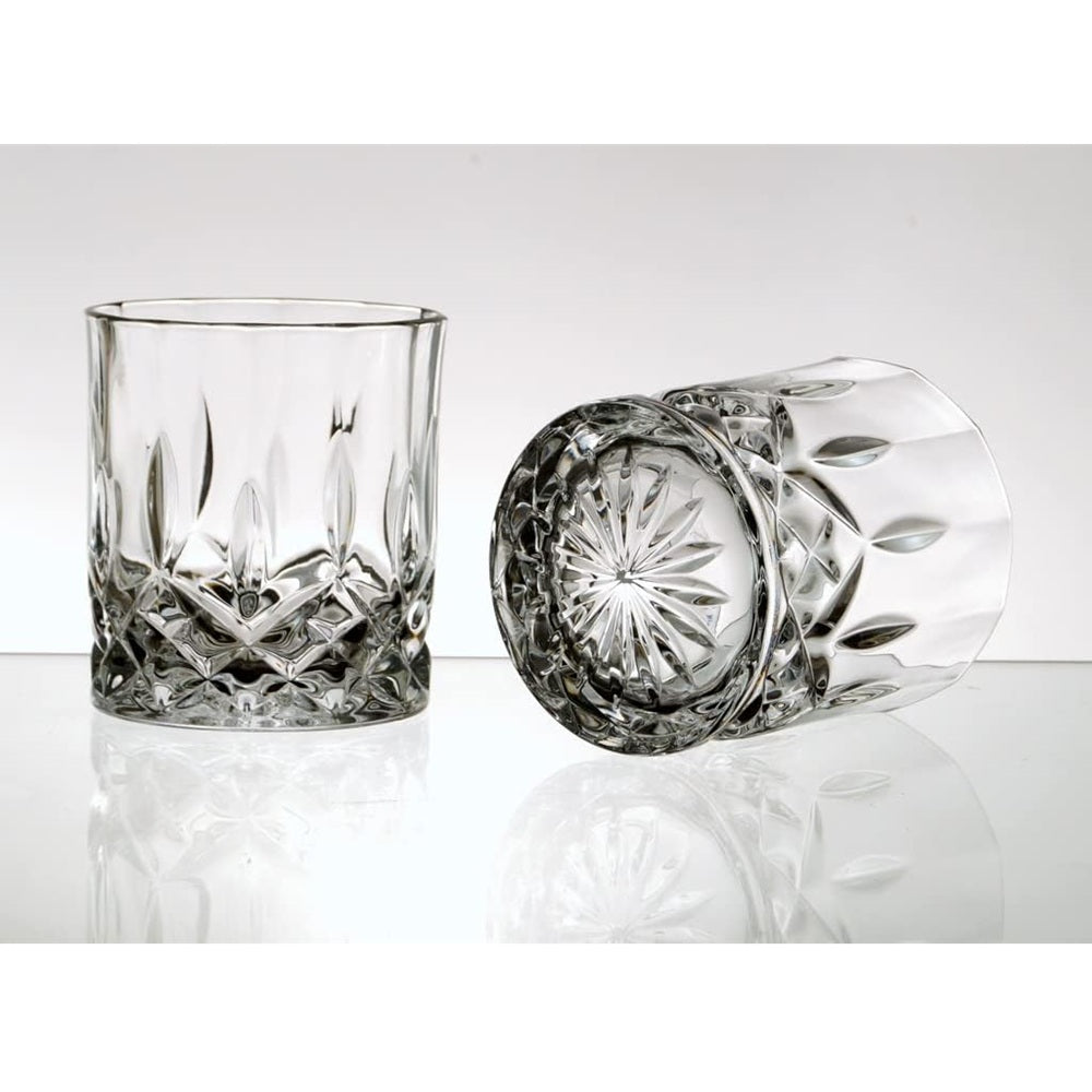 Two crystal glasses with intricate designs on a reflective surface.