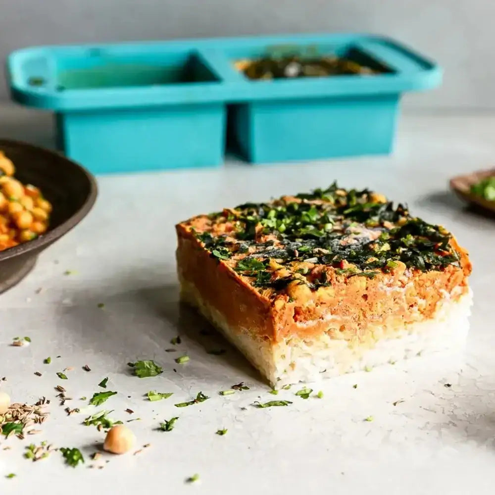 Vegetarian meatloaf with herbs on a light surface, with a teal silicone mold in the background.