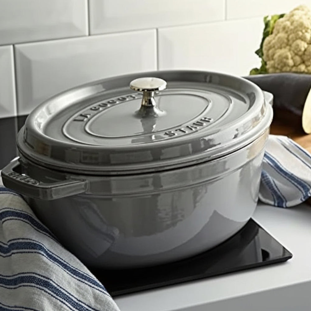 Grey cocotte pot on an induction hob next to a wooden chopping board with vegetables