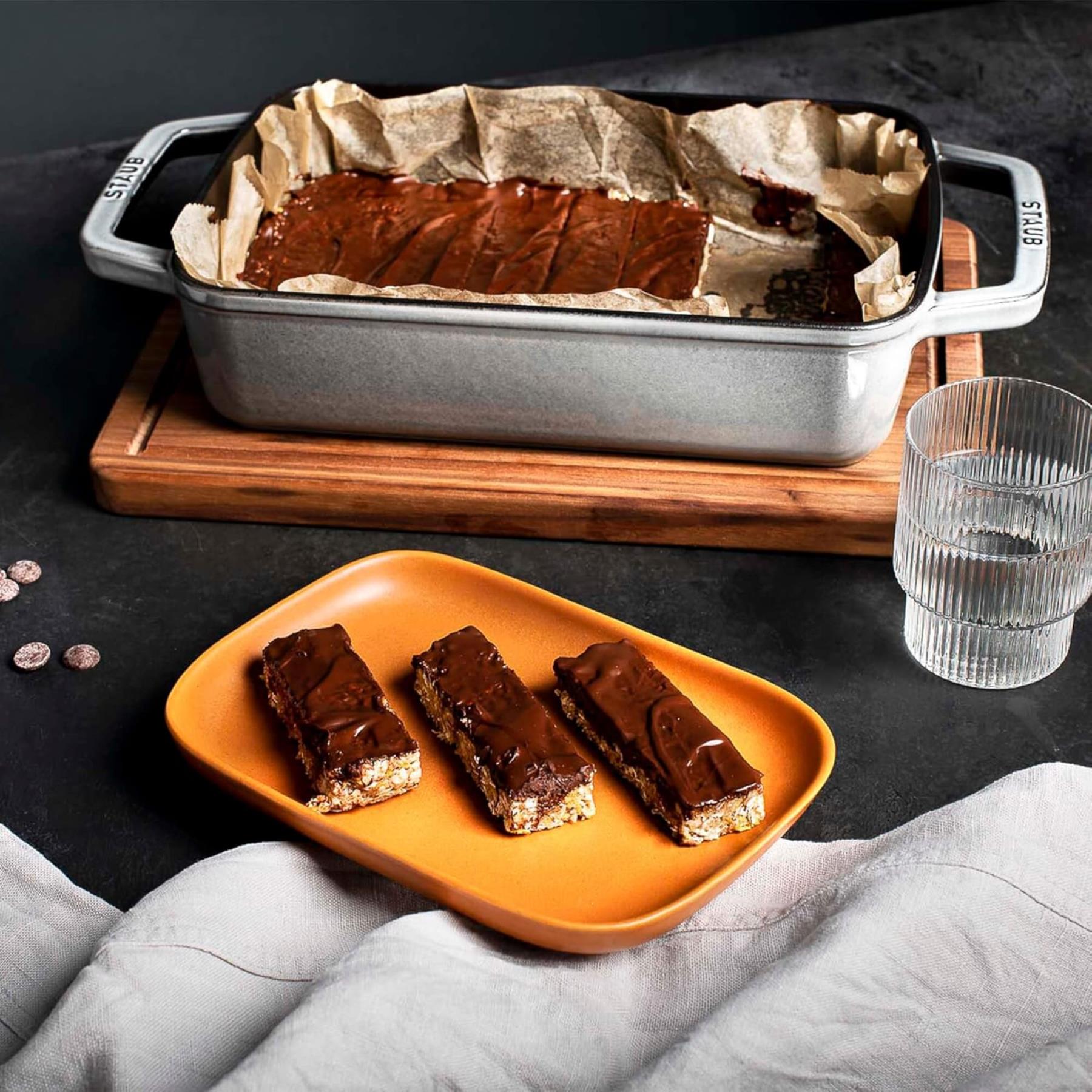 Chocolate bars on an orange plate with a baking pan in the background