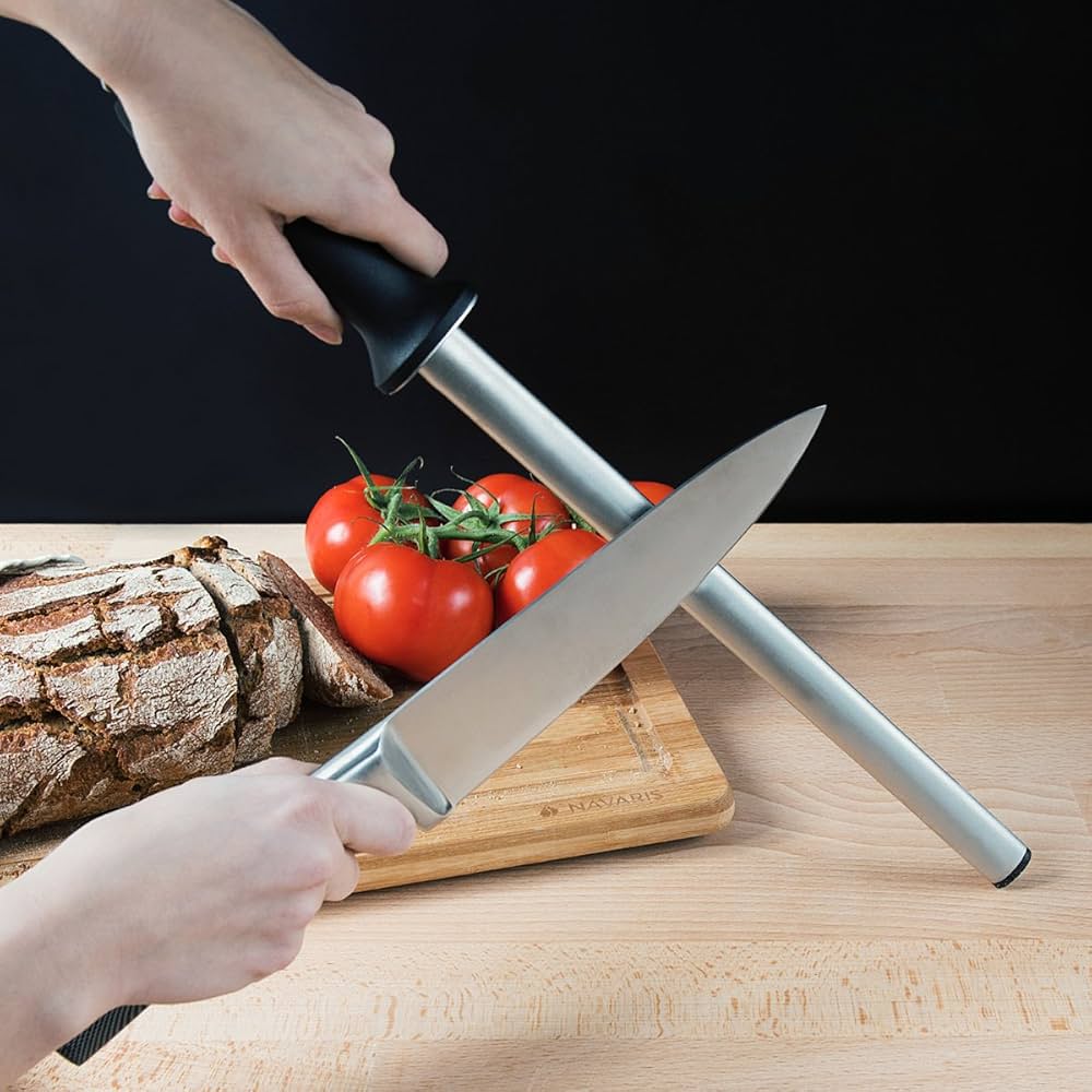 Knife sharpener being used on a chef's knife with bread and tomatoes in the background