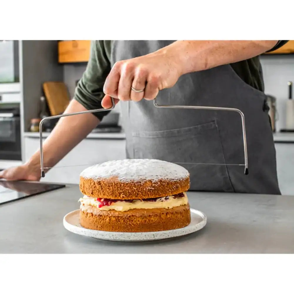 Person cutting a layered cake with a knife in a kitchen setting