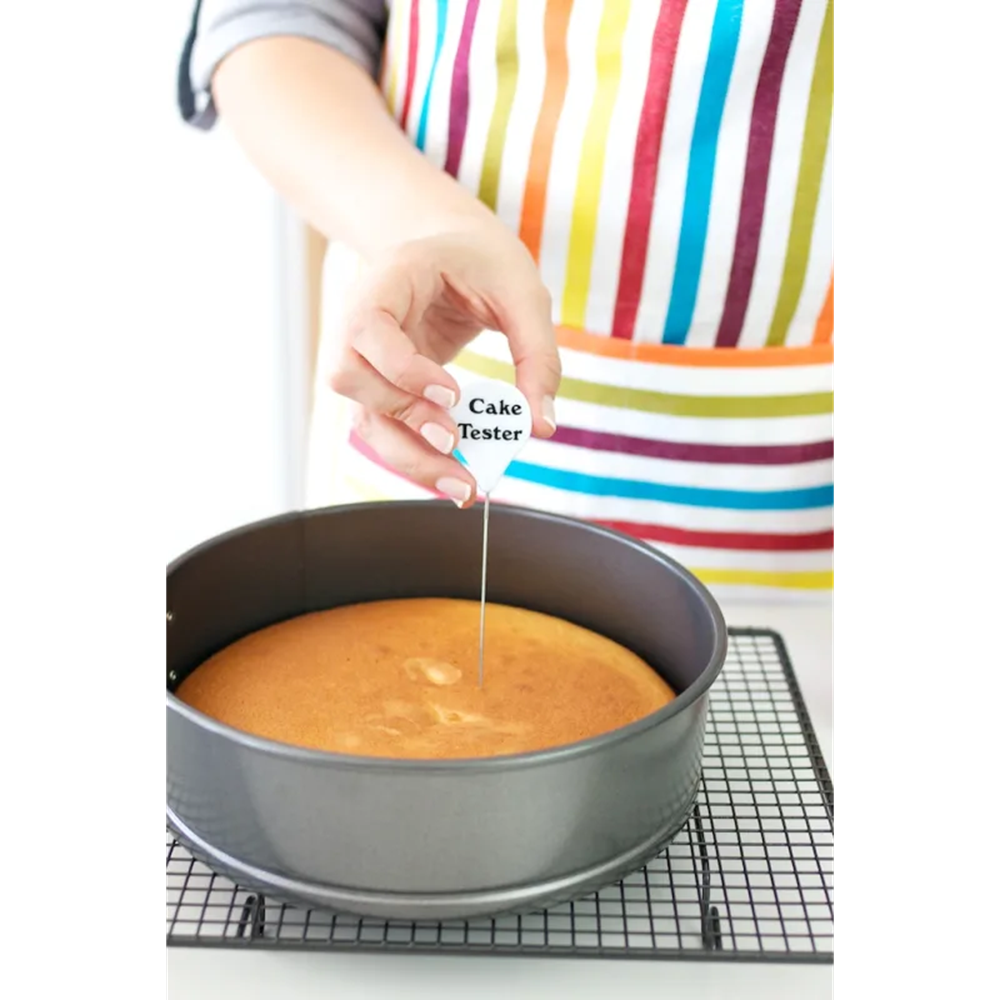 Person using a cake tester to check the doneness of a baked cake.