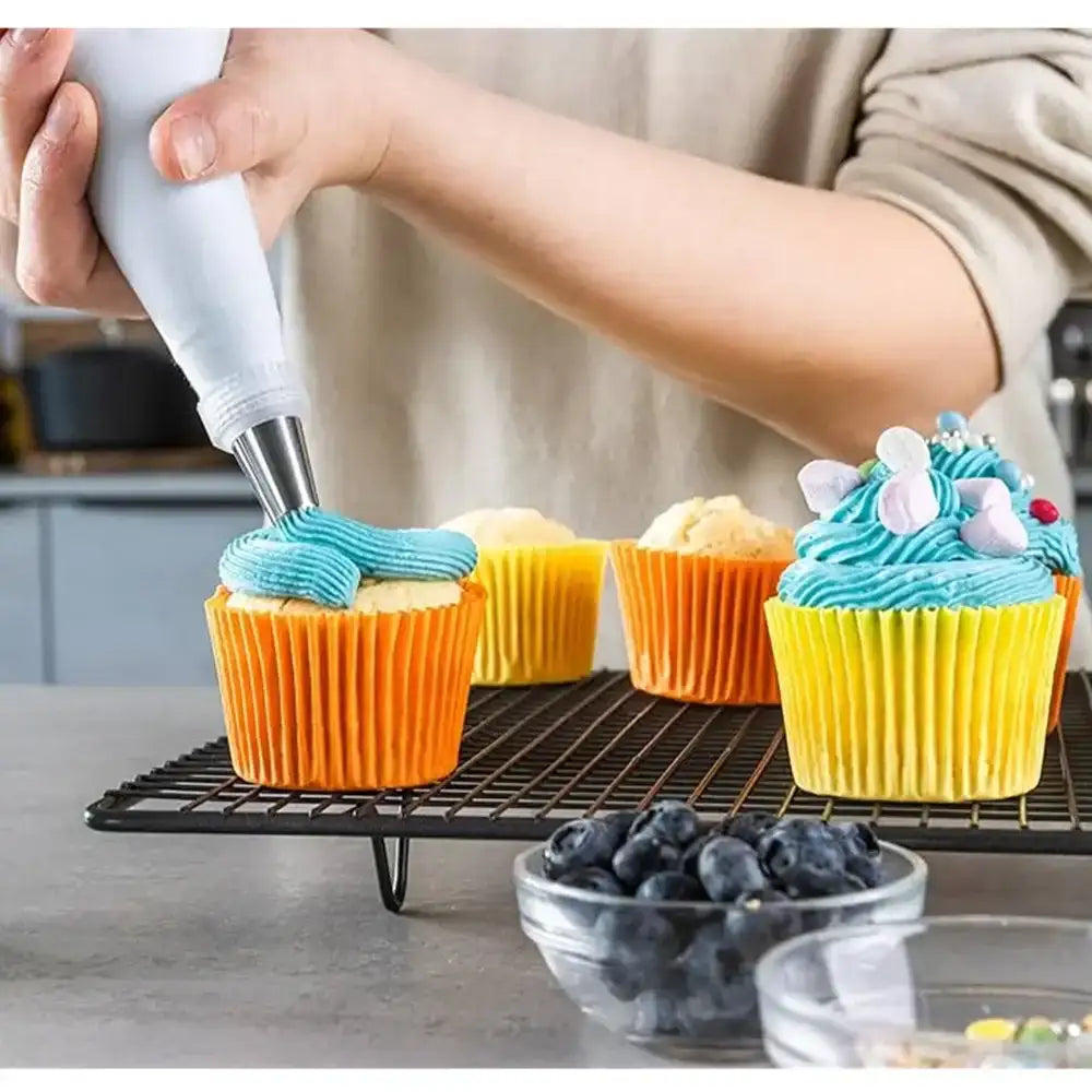 Person decorating cupcakes with blue frosting on a kitchen counter.
