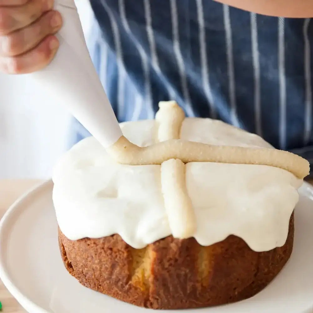 Person icing a bundt cake with white frosting