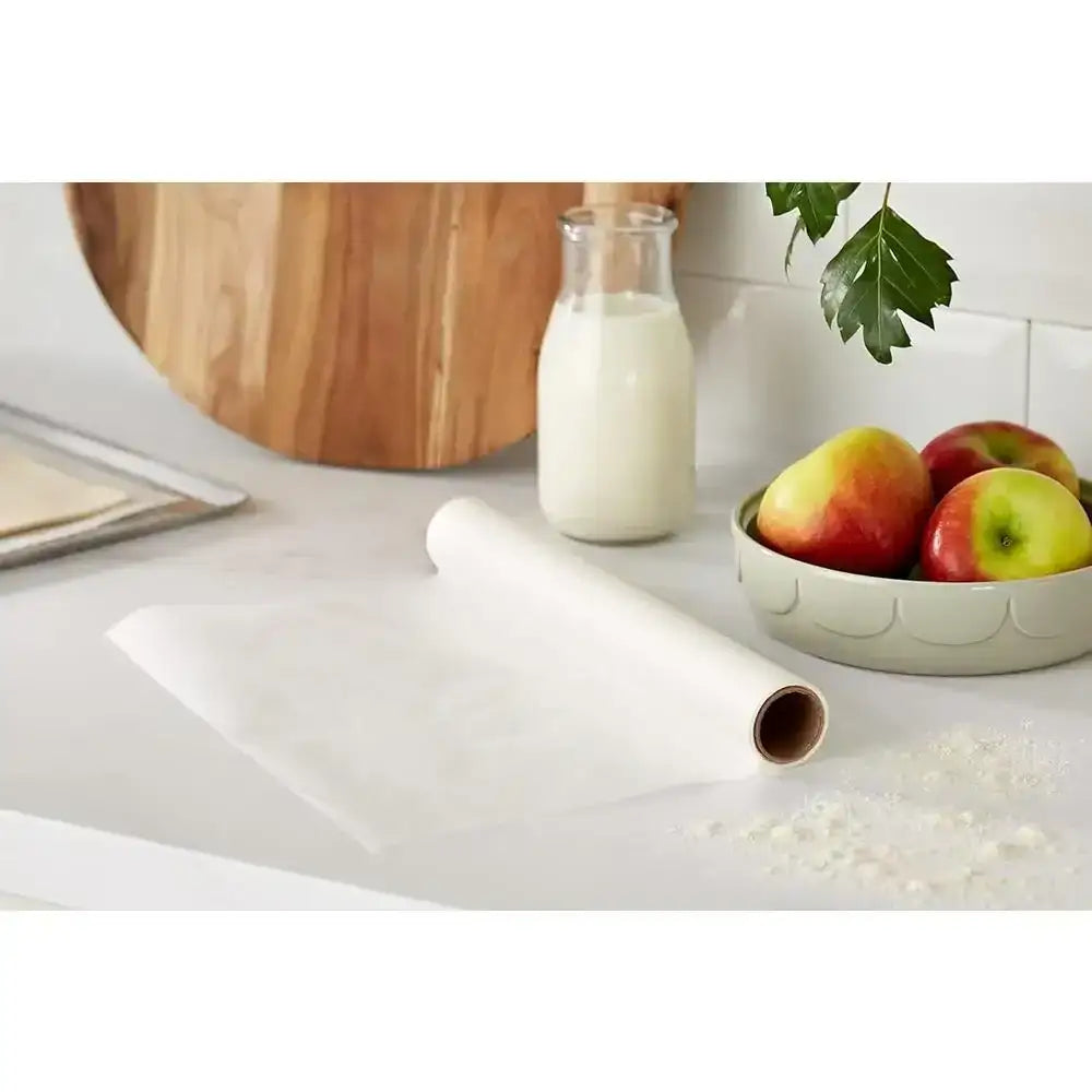 Roll of white paper on a kitchen counter with a bottle of milk and apples in the background.