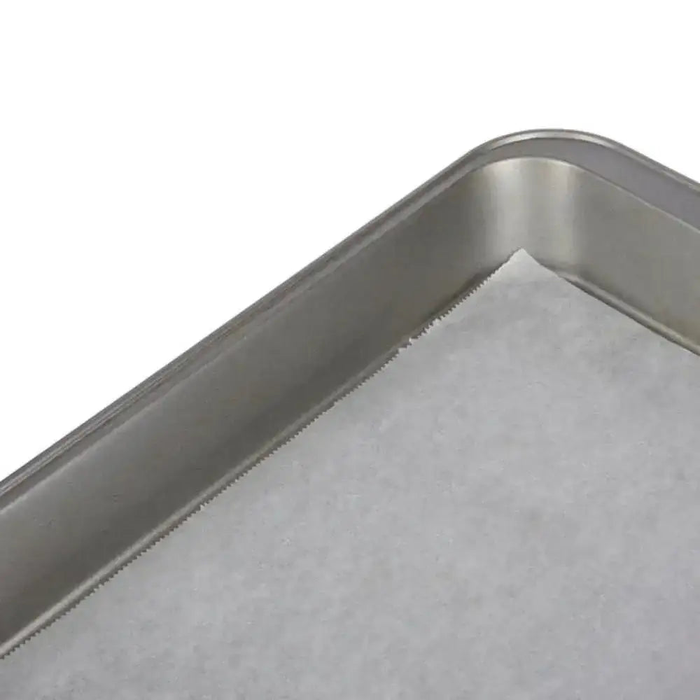 Stainless steel baking tray with parchment paper on a white background