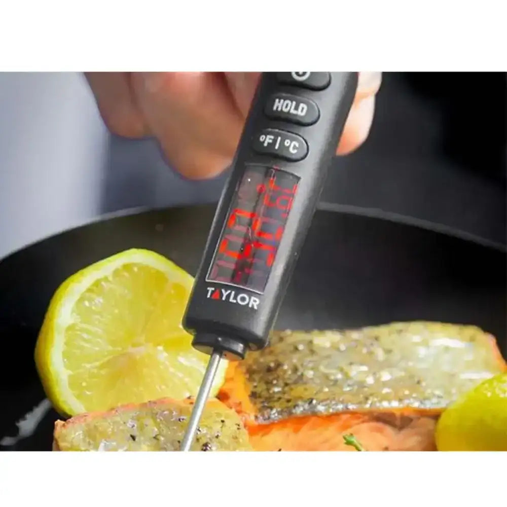 Digital thermometer inserted into a piece of salmon with a lemon wedge, displaying temperature.