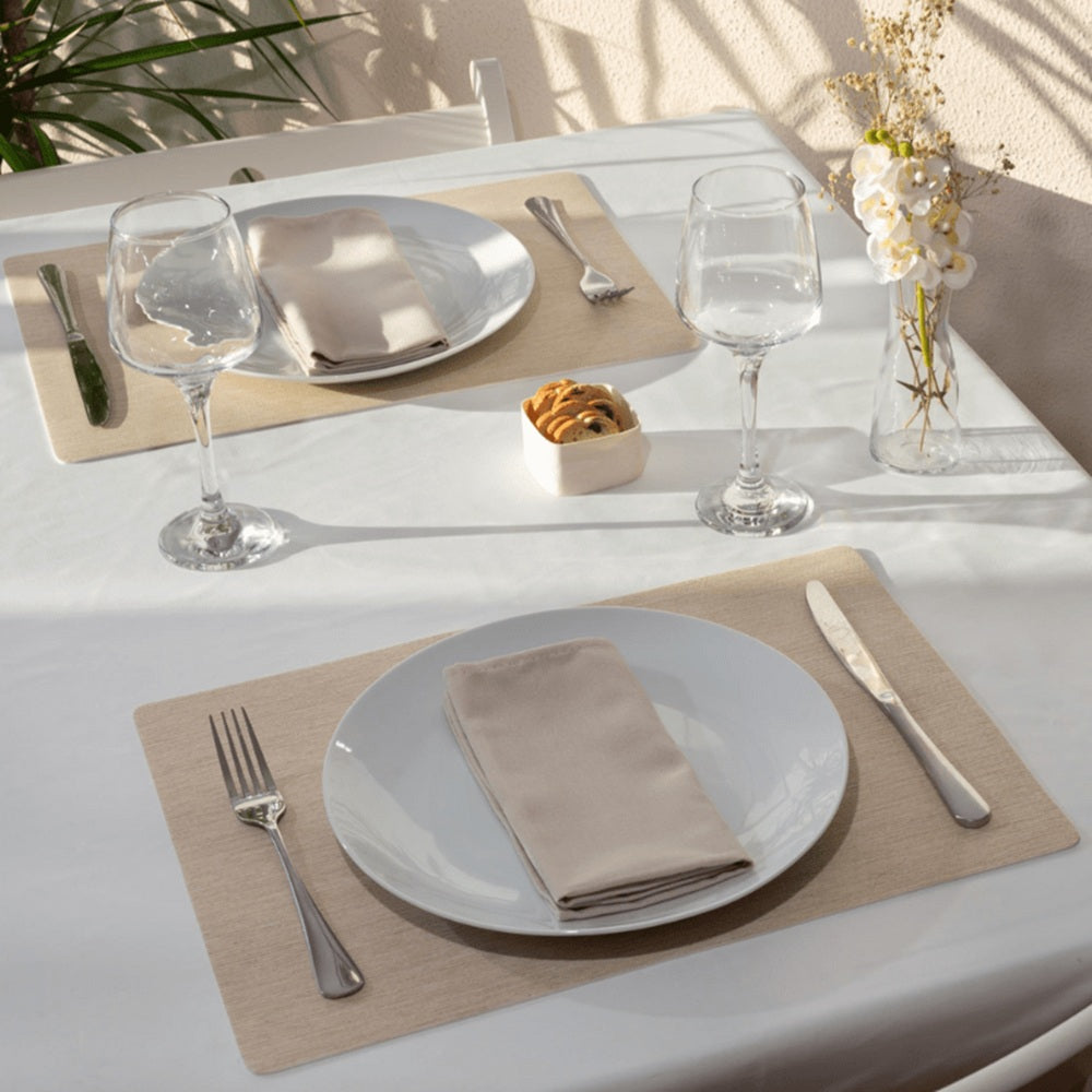 Dining table setting with plates, glasses, and cutlery on a white tablecloth.