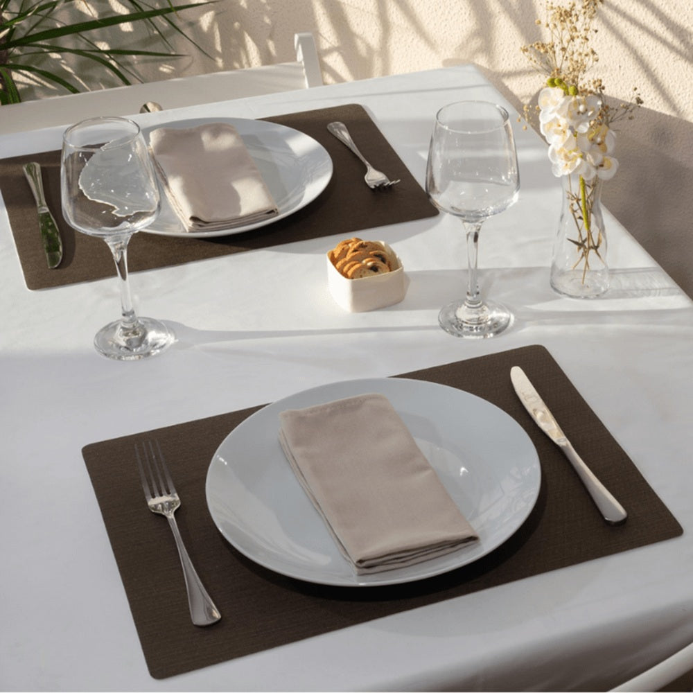 Dining table setting with plates, glasses, and cutlery on a white tablecloth.
