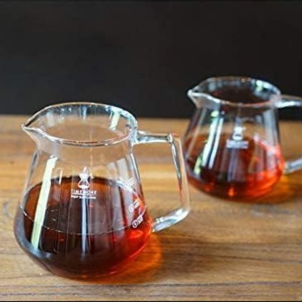 Two glass pitchers filled with a dark liquid on a wooden surface.