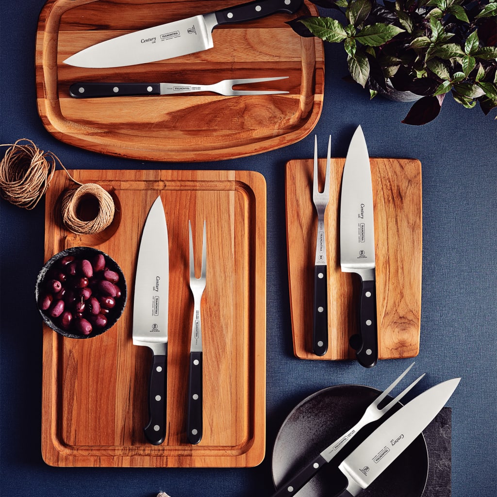 Set of knives and cutting boards on a blue surface with a plant in the corner.