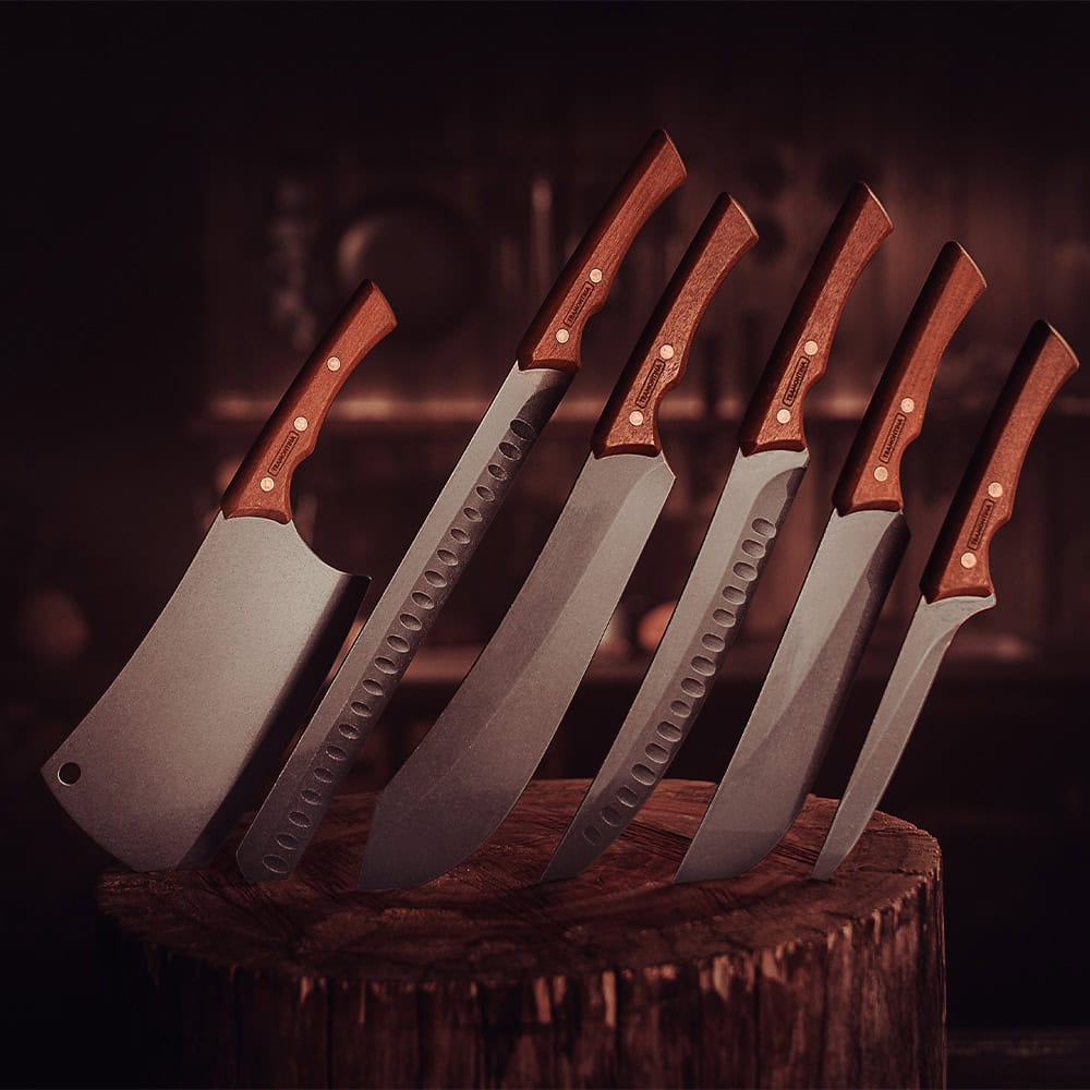 Set of five machetes with wooden handles on a wooden block against a dark background
