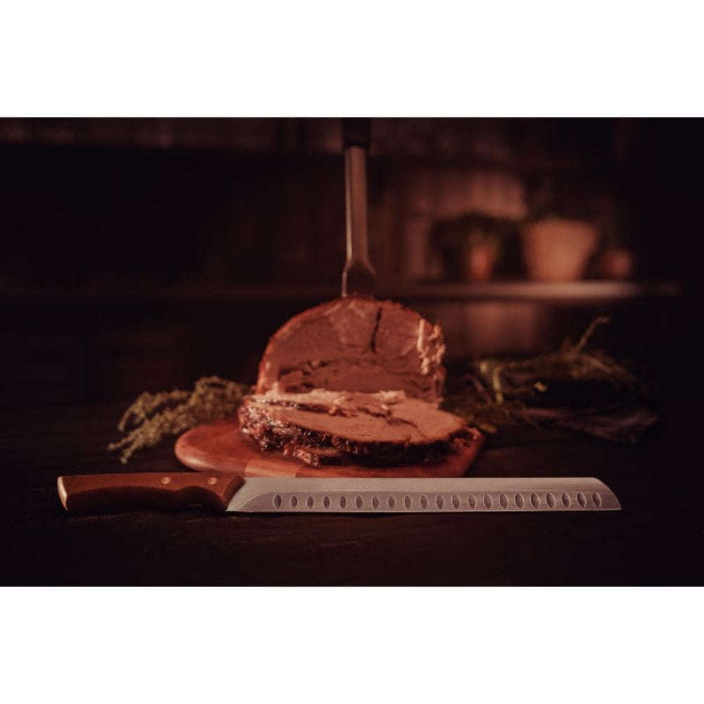 Loaf of bread on a wooden cutting board with a knife in a warm-toned setting