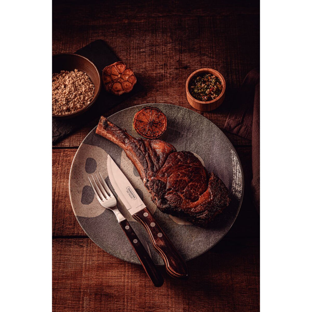 Cooked meat on a plate with a knife and fork set 