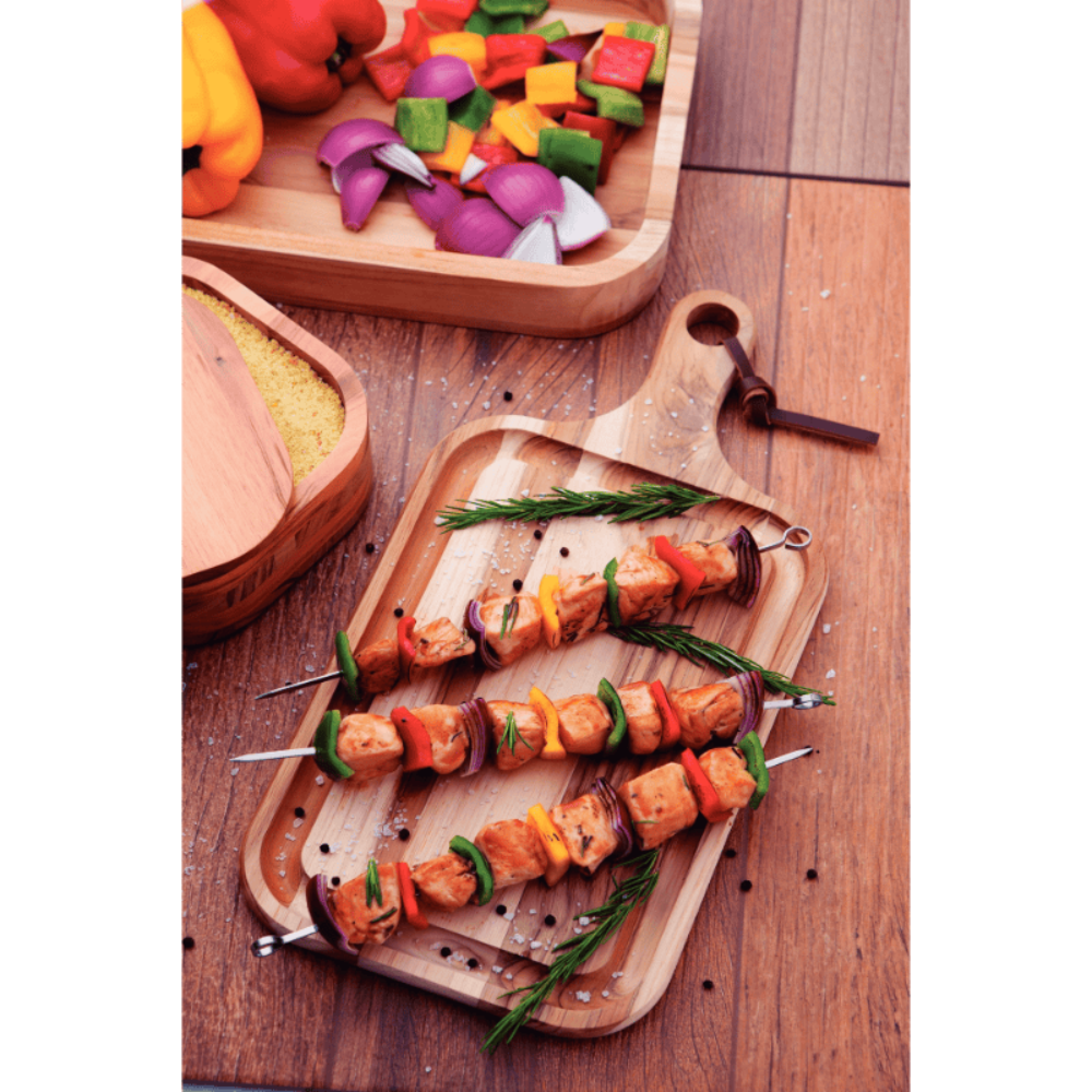 Cooked meat and vegetables on skewers with a wooden surface.