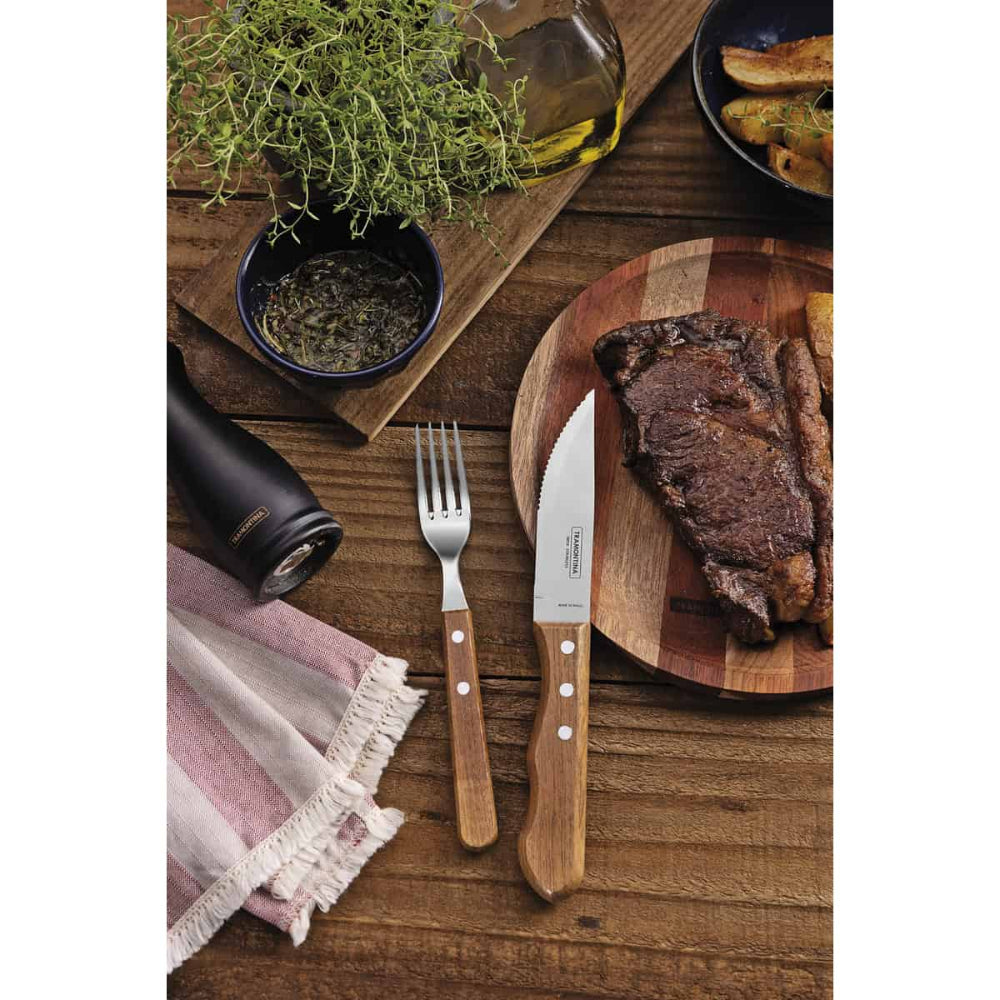 Steak on a wooden cutting board with a knife, fork, and various items on a wooden table.