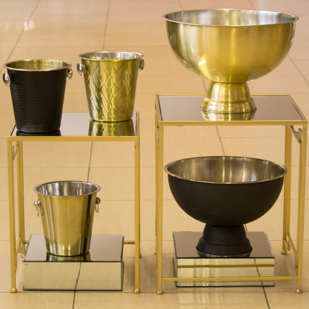 Set of gold and black metal bowls and buckets on a tiled floor.
