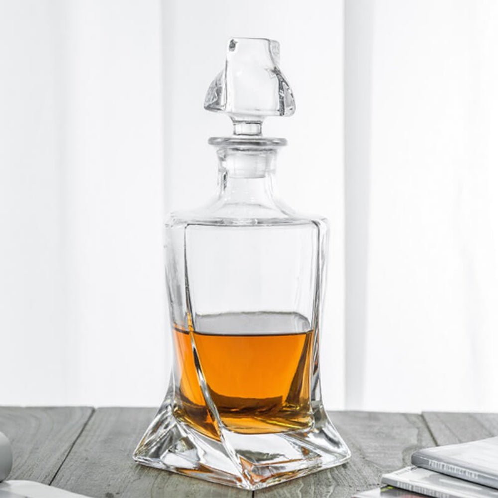 Clear glass whiskey decanter with amber liquid on a wooden surface.