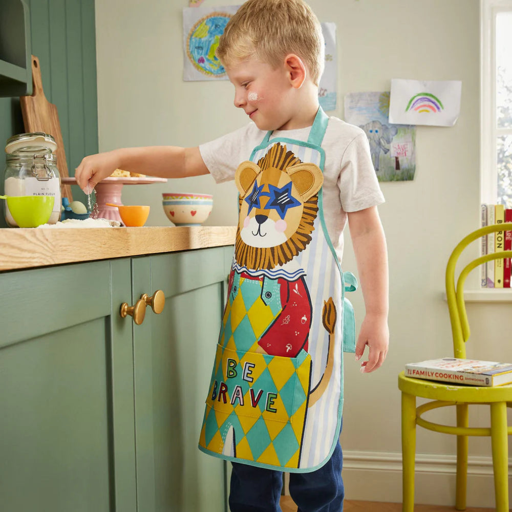 Child wearing a colorful lion apron in a kitchen