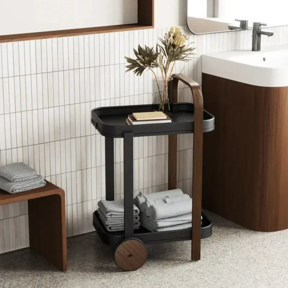Bathroom setting with a black cart, towels, and a sink.