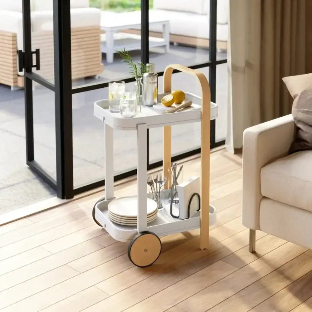 White serving cart with wooden handle in a living room setting