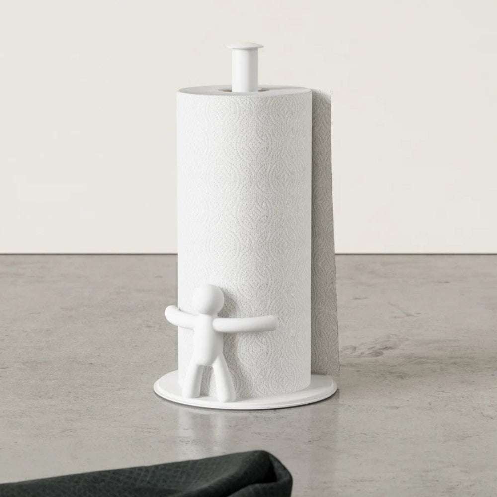 White paper towel holder with a cylindrical paper towel roll on a light wooden floor.