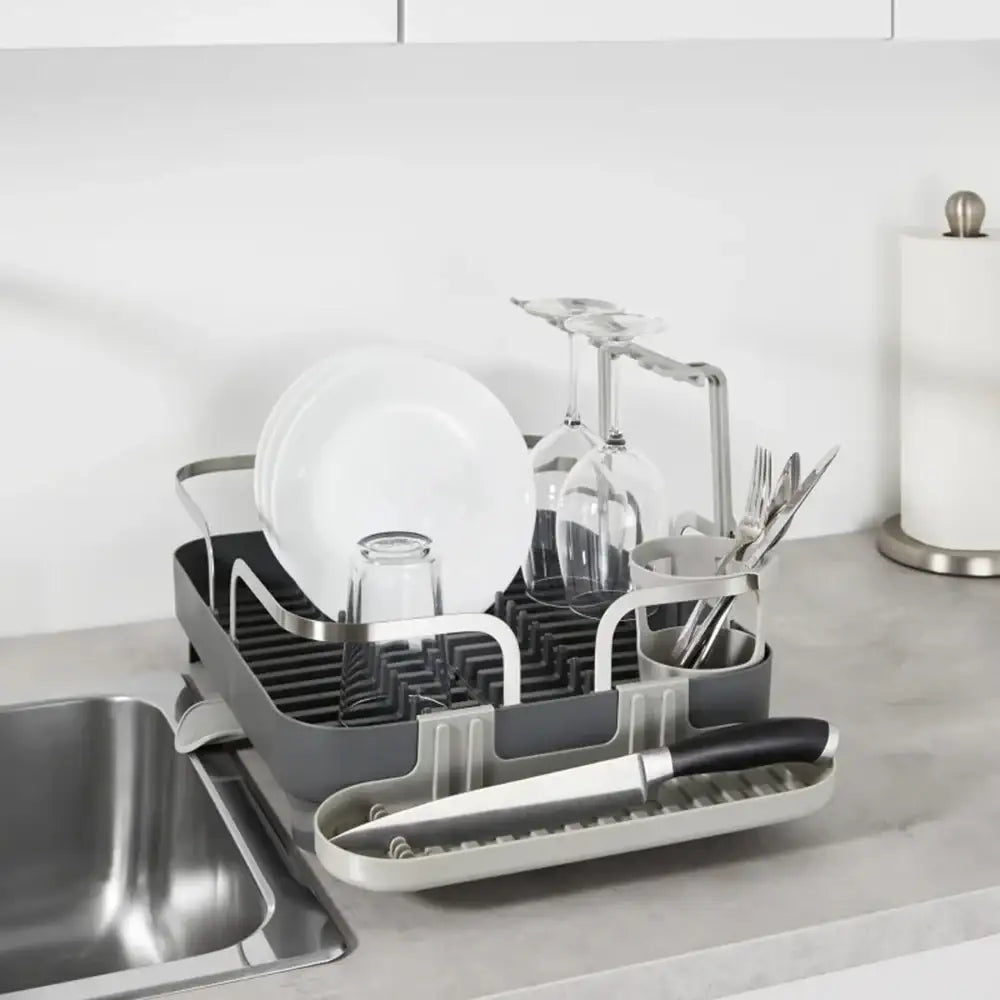 Dish drying rack with dishes on a kitchen counter next to a sink.