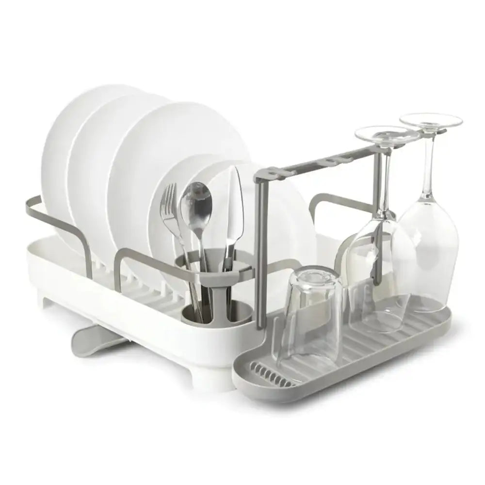 Dish drying rack with white plates, glasses, and cutlery on a white background
