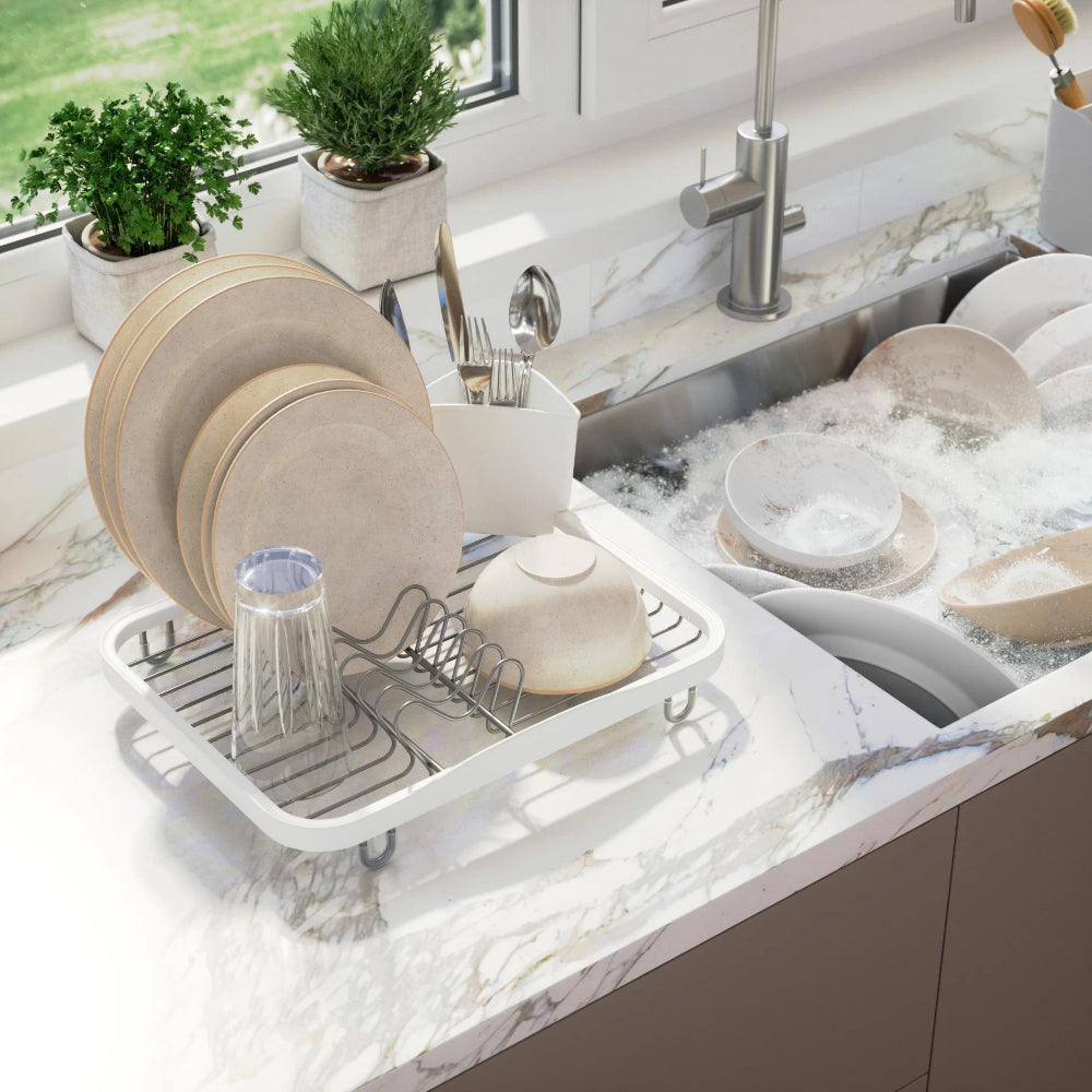 Dish rack with dishes on a kitchen counter next to a sink.