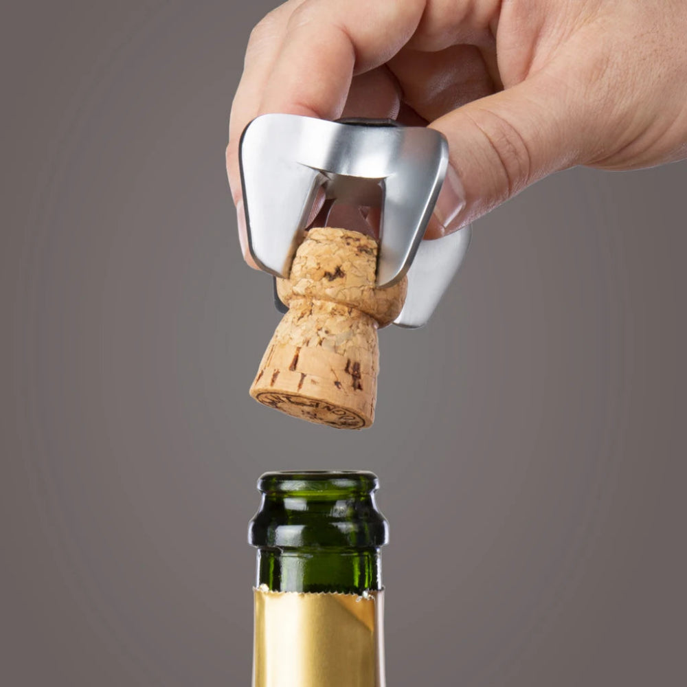Hand using a bottle opener to remove a cork from a wine bottle on a gray background