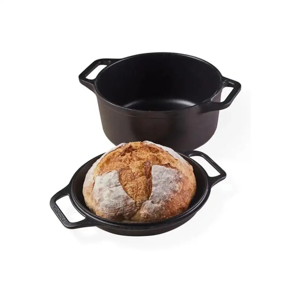 Black cast iron pot with a loaf of bread on a white background