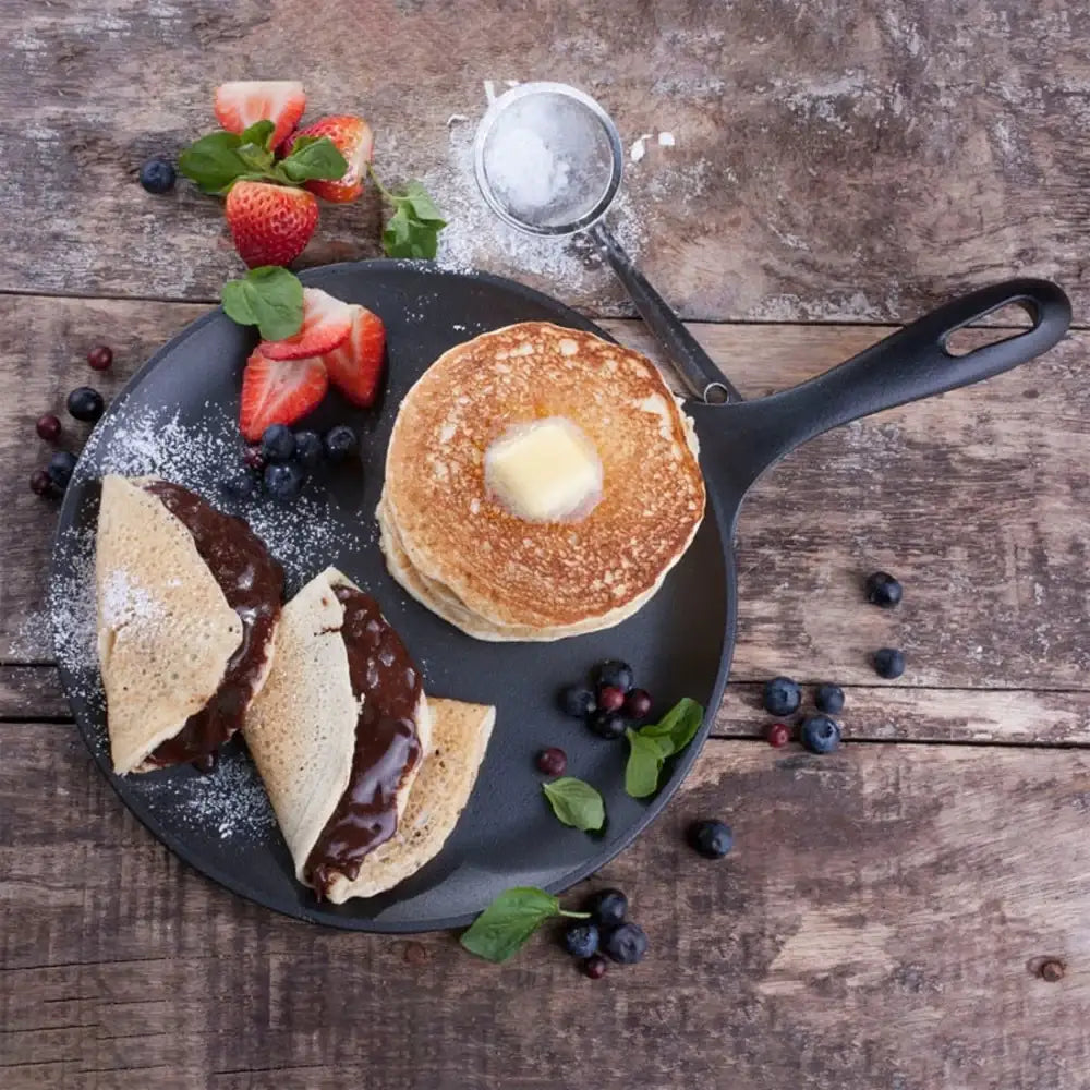 Stack of pancakes with a side of fruit on a wooden table